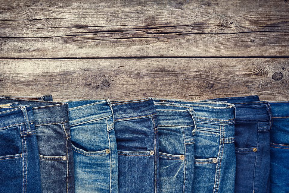 Fashion different jeans on wooden background. Retro toned.